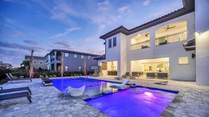 Et moderne hus med swimmingpool, udendørs siddepladser og en veloplyst terrasse.