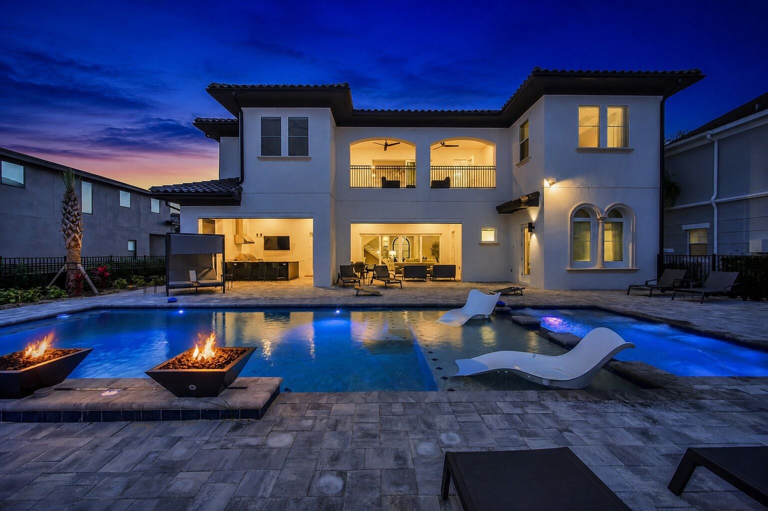 A two-story house with a swimming pool, outdoor seating, and a fire pit.