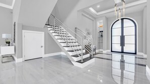 Et rummeligt, moderne interiør med en blankpoleret trappe, en stor buegang og et minimalistisk design.