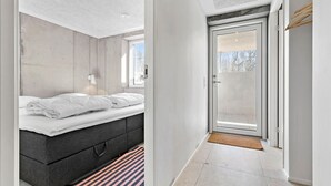 Ett modernt sovrum med en stor säng, ett nattduksbord och ett fönster.