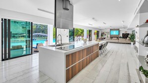 A modern kitchen with a central island, a dining area with a sofa, and a view of a swimming pool.