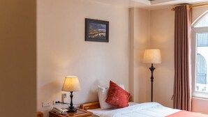 A hotel room with a bed, two bedside lamps, a nightstand with a telephone, a painting on the wall, and a window with curtains. - Thu Hang Sapa Hotel - by Bay Luxury (Sa Pa)