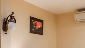 A hotel room with a bed, a bedside lamp, a nightstand with a phone, a wall-mounted air conditioner, and a framed picture on the wall. - Thu Hang Sapa Hotel - by Bay Luxury (Sa Pa)