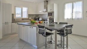 A modern kitchen with a central island, stainless steel appliances, and a bar area with stools.