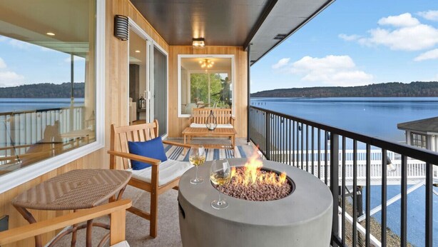 A balcony with a fire pit, seating, and a view of a lake.