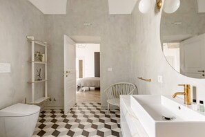 Een moderne badkamer met een witte wasbak, een gouden kraan en een zwart-witte vloer.