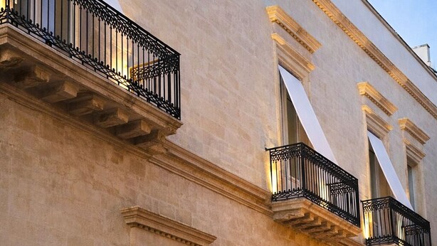 Um edifício com várias varandas, janelas amplas e detalhes arquitetônicos clássicos.