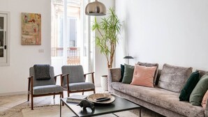 Uma sala de estar com sofá, duas poltronas, mesa de centro e uma planta grande.