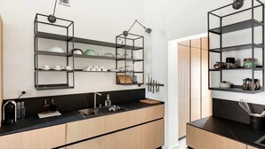 Uma cozinha moderna com bancadas pretas, armários de madeira e prateleiras de metal.