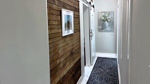 A hallway with wooden paneling, a white door, and a black rug.