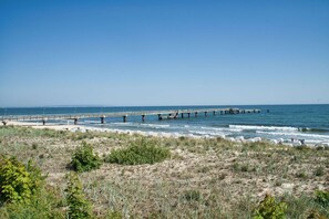 A coastal area with a long pier extending into the sea, a sandy beach with lounge chairs, and sparse vegetation. - im Zentrum Gelegene 2-raum-wohnung - Haus Rugier Fewo 03 - Haus Rugier (Göhren)