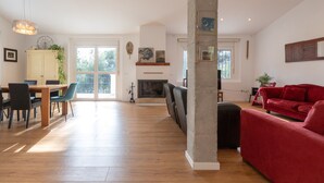 A spacious living area with a wooden floor, a red sofa, a dining table with chairs, and a fireplace. - AXARQUÍA - Wonderful country house with above ground pool and Free WiFi (Málaga)