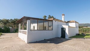 A small, white building with a tiled roof, a large window, and a door.