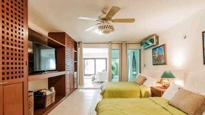 Une chambre d’hôtel avec deux lits, une télévision, un ventilateur de plafond et une vue sur l’extérieur.