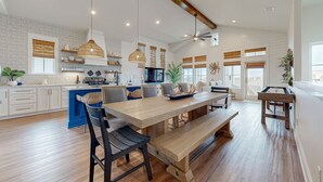 Une cuisine spacieuse avec une longue table en bois, des placards intégrés et des luminaires suspendus.