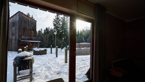 A view through a window of a snowy outdoor area with a wooden building and trees.