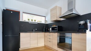 A modern kitchen with a black refrigerator, wooden cabinets, a microwave, and a built-in oven.