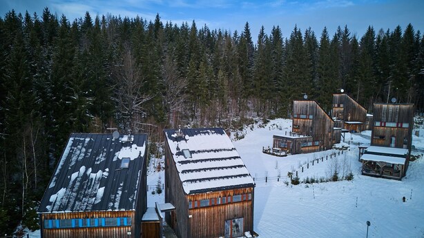 A cluster of wooden cabins in a snowy forest.