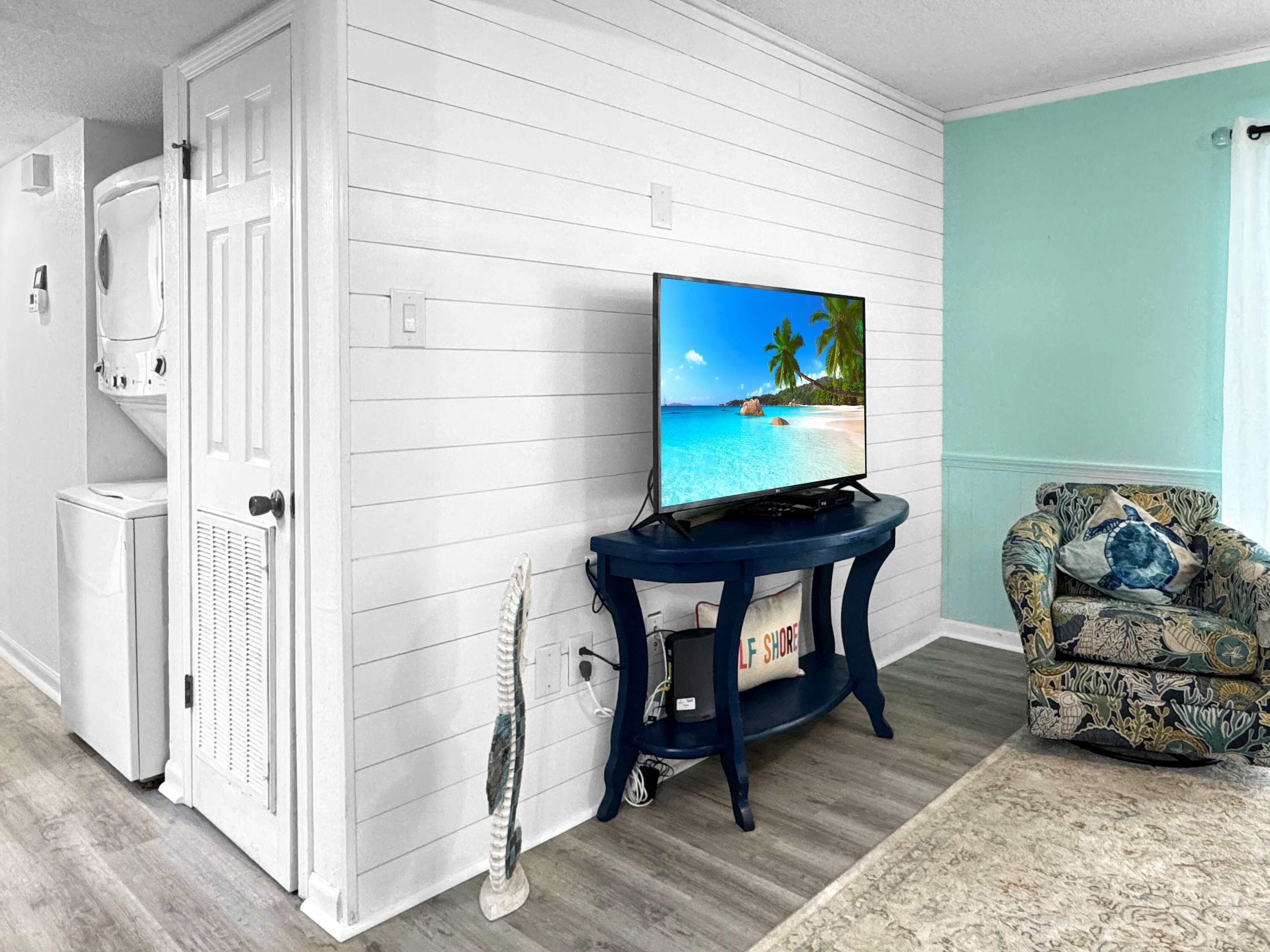 A living room with a television on a stand, a patterned armchair, and a decorative item on the floor.