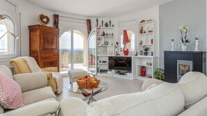 Een ruime woonkamer met een groot raam, een open haard en een gezellige zithoek.