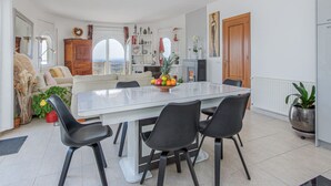 Een moderne eetruimte met een witte tafel, zwarte stoelen en uitzicht op de omgeving.