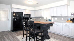 A kitchen with white cabinets, a black refrigerator, a wooden island, and a black chair. - Caddy Shack 2- Charming 3-bedroom totally remodeled with AC and WiFi in Montrose (Montrose)