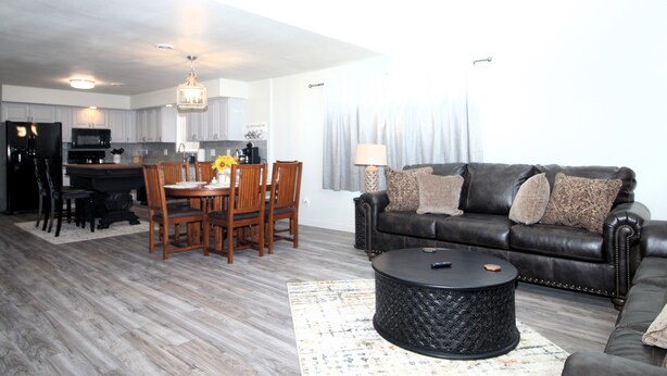 A modern living room with a black leather sofa, a round coffee table, and a dining area with wooden chairs and a table. - Caddy Shack 2- Charming 3-bedroom totally remodeled with AC and WiFi in Montrose (Montrose)