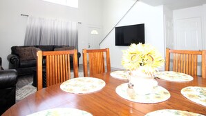 A dining area with a wooden table, floral placemats, and a vase with sunflowers. - Caddy Shack 2- Charming 3-bedroom totally remodeled with AC and WiFi in Montrose (Montrose)