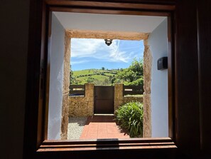 A doorway leading to a courtyard with a stone wall, a gate, and a view of rolling hills. - Casa La Escuelina en Villanueva (Villanueva)