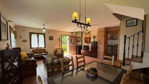 Amplia sala de estar con una mesa de comedor de vidrio, un conjunto de sofá y una chimenea.