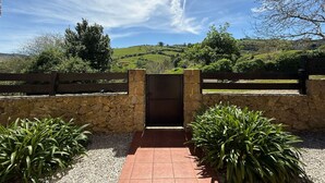Un arco de piedra que da acceso a un patio con vistas a colinas onduladas y un cielo despejado.