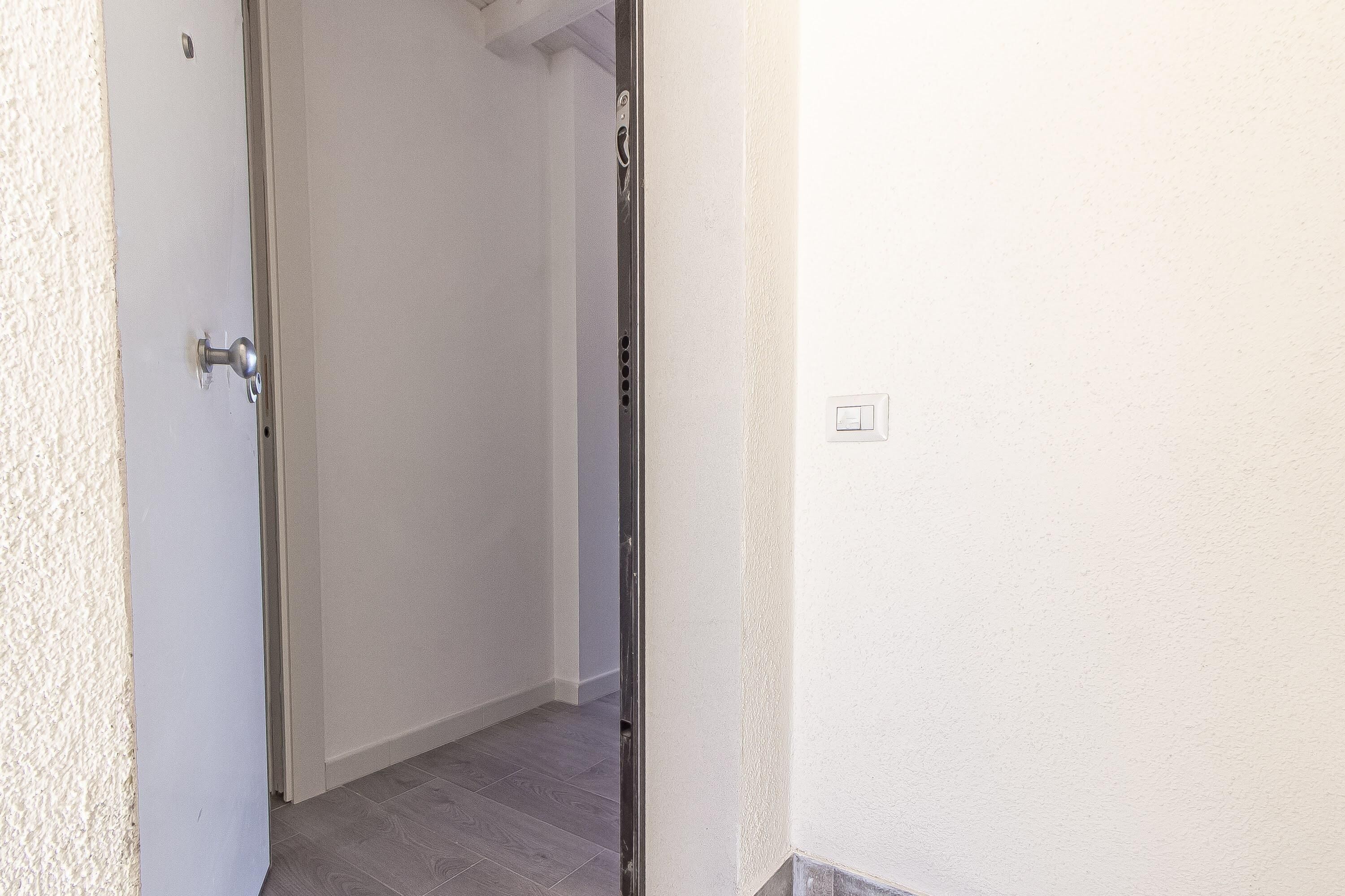 Ein Flur mit einer weißen Tür und einem Lichtschalter an der Wand.