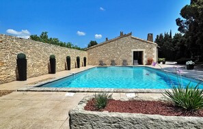 Un edificio in pietra con una piscina, un muro di pietra e un'apertura che conduce all'edificio.