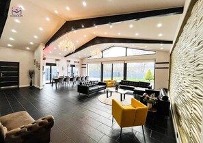 Amplia sala de estar con techo alto, muebles modernos y ventanas grandes que ofrecen vistas al exterior.