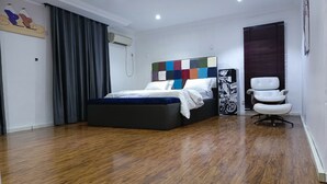 Ein modernes Schlafzimmer mit einem großen Bett, einem Sessel und einem farbenfrohen Kopfteil.