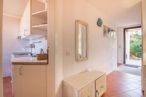 A kitchen with white cabinets, a wooden countertop, a sink, and a mirror.
