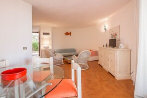 Une pièce comprenant une table à manger, des chaises, un canapé, un téléviseur et un meuble.