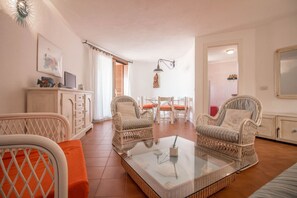 A living room with wicker furniture, a glass coffee table, and a dining area with a table and chairs.