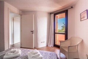 Une chambre à coucher avec un lit, une chaise, une porte et une vue par la fenêtre.