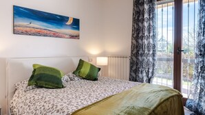 A bedroom with a bed, a painting, a window with curtains, and a radiator. - GuestHost - Arezzo Equestrian Centre-Apt W/ Private Parking! (Arezzo)