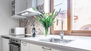 A modern kitchen with a microwave, oven, sink, and decorative vase with flowers. - GuestHost - Palazzo dei Normanni & Ballarò Roomy Modern Apt x9 (Palermo)