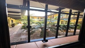 A view through a window with metal bars, revealing a courtyard with potted plants and a tiled floor. - Infantes Street, Center of Seville (Sevilla)