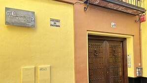 A yellow building with a large wooden door, a fire safety sign, and a number '30' on the wall. - Infantes Street, Center of Seville (Sevilla)