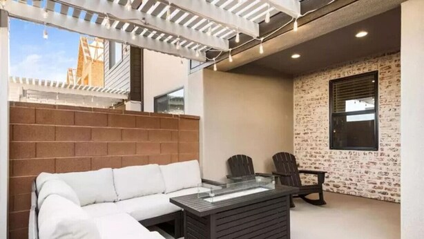 Een terras met een witte bank, een tafel met glazen blad en twee stoelen.