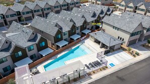 Un complesso residenziale con diverse case a due piani, una piscina in comune e un'area parcheggio riservata.