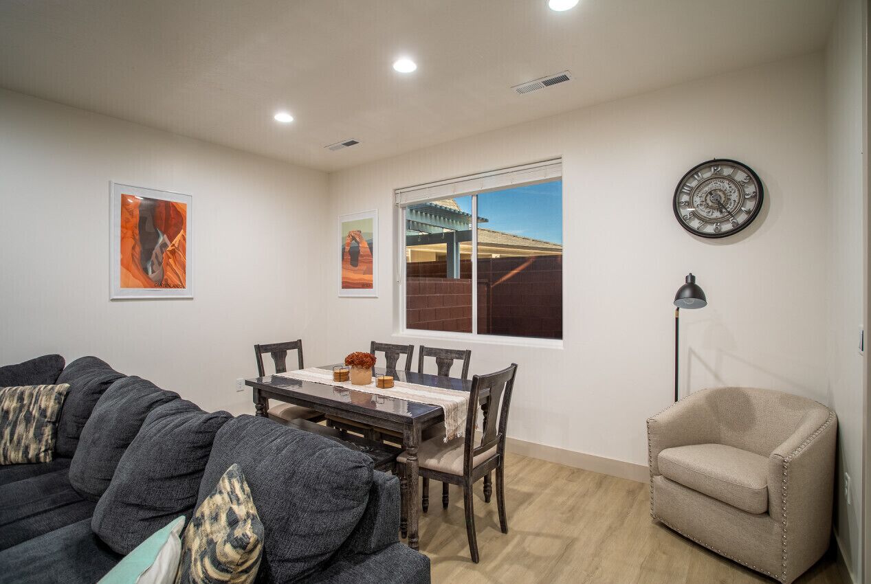 A dining area with a table, chairs, a sofa, and a lamp.