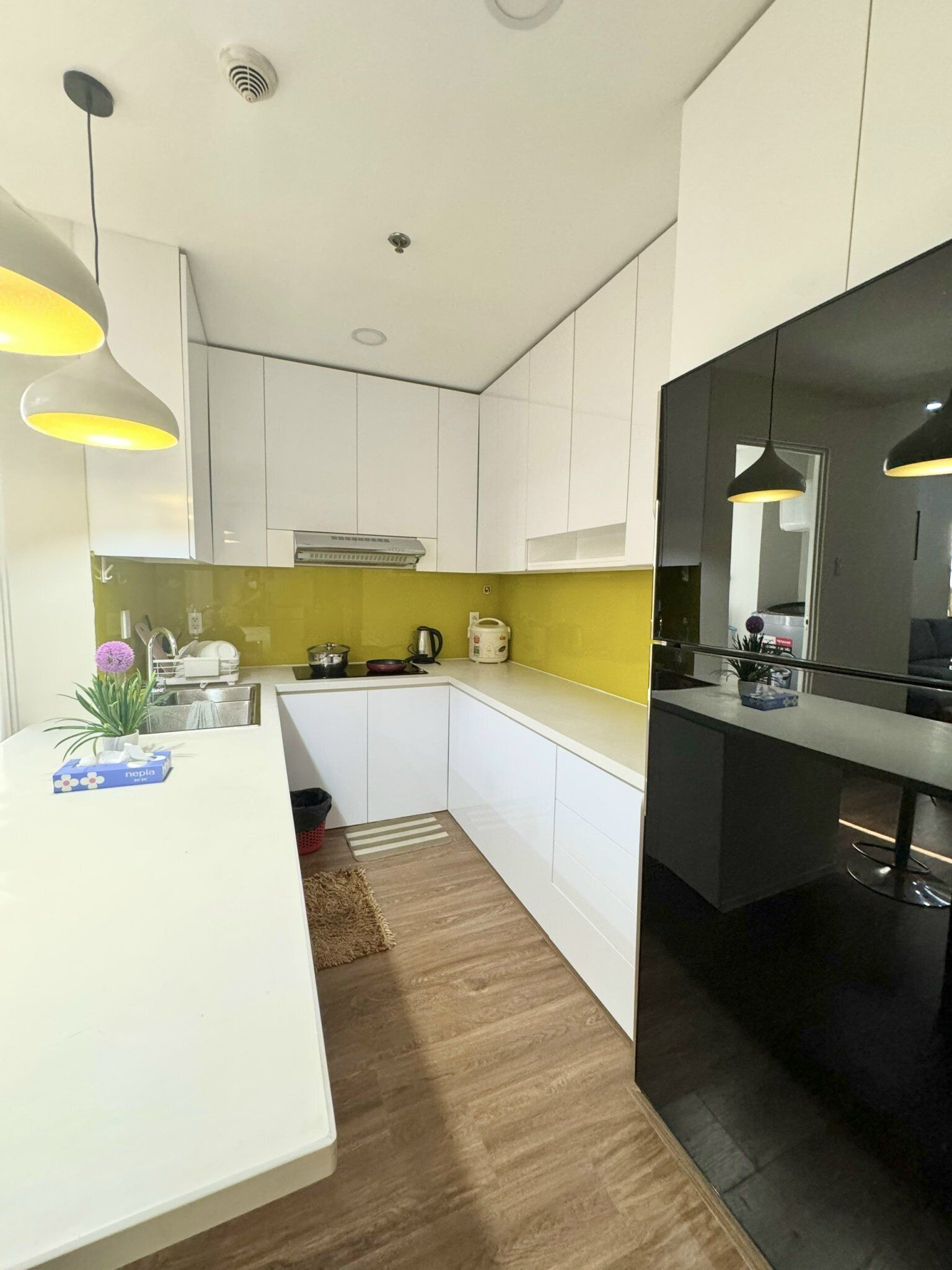 A modern kitchen with white cabinets, a yellow backsplash, and a black countertop.