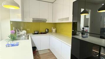 A modern kitchen with white cabinets, a yellow backsplash, and a black countertop.