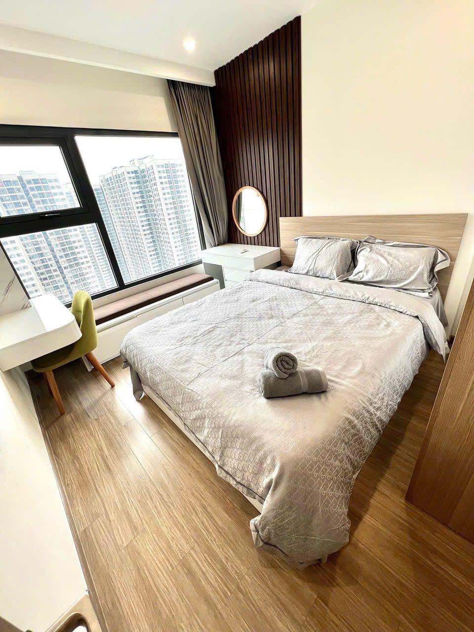 Habitación de hotel moderna con una cama grande, un escritorio y vistas a edificios altos.