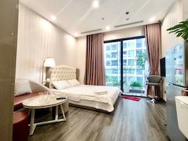 Quarto de hotel com cama, mesa redonda pequena, sofá, televisão e frigorífico.